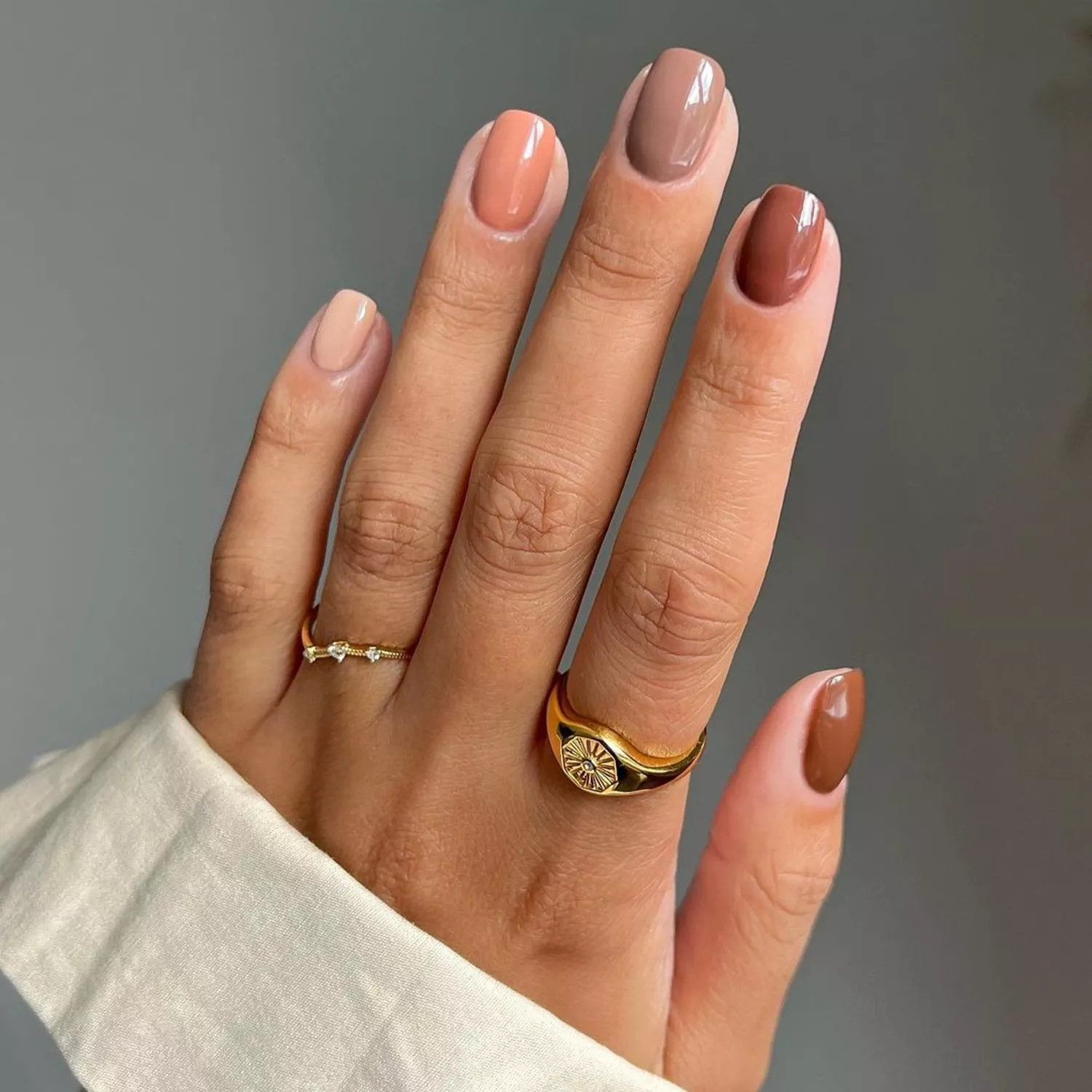 Close up of a glossy manicure in shades of brown, beige, and caramel