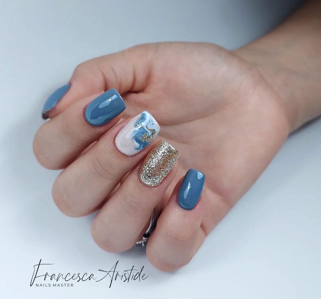 Blue, white, and gold nail colors with marble nail art on short tapered square nails