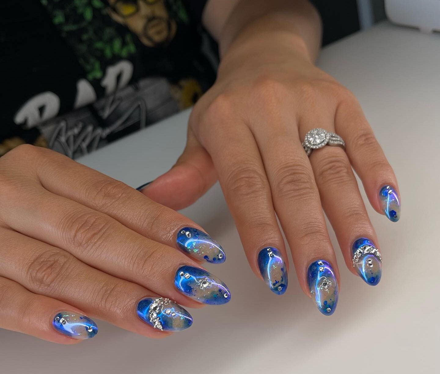 Chrome blue abstract nail art with rhinestones on long almond nails