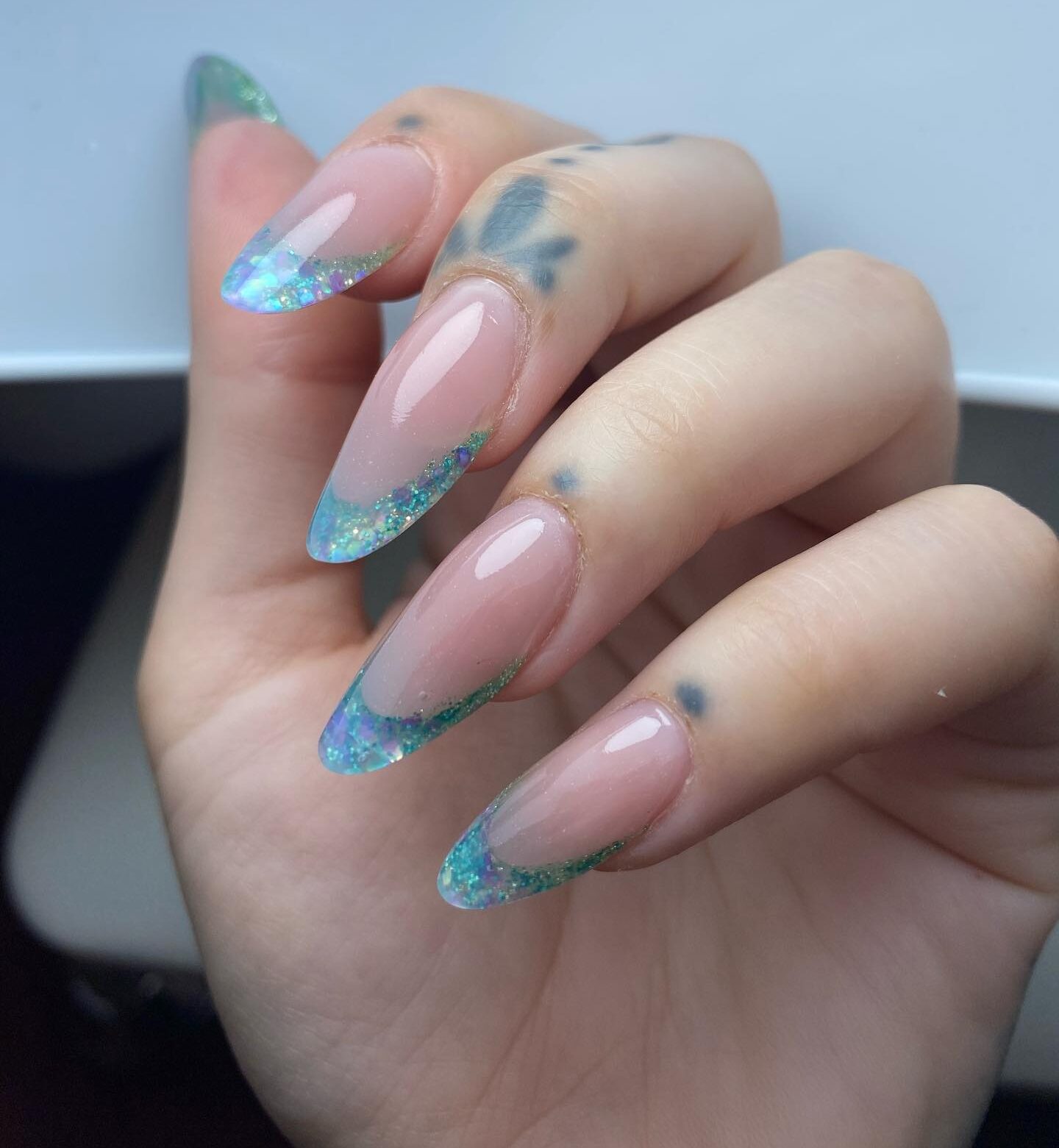 Glittery blue French tips on long round shaped acrylic nails