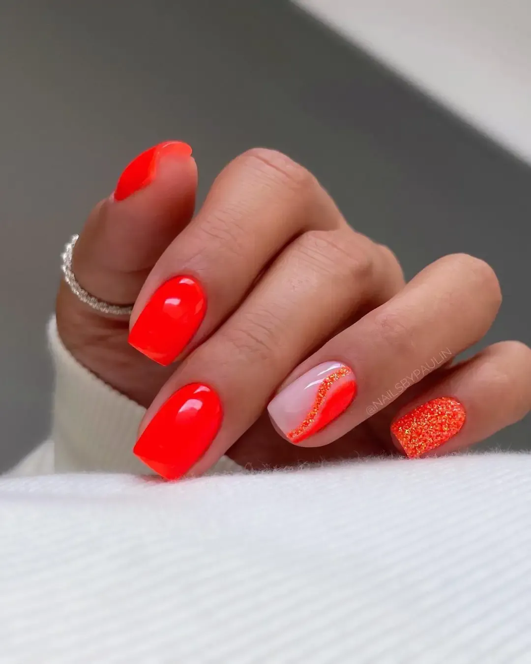 Neon orange nails with glitter.