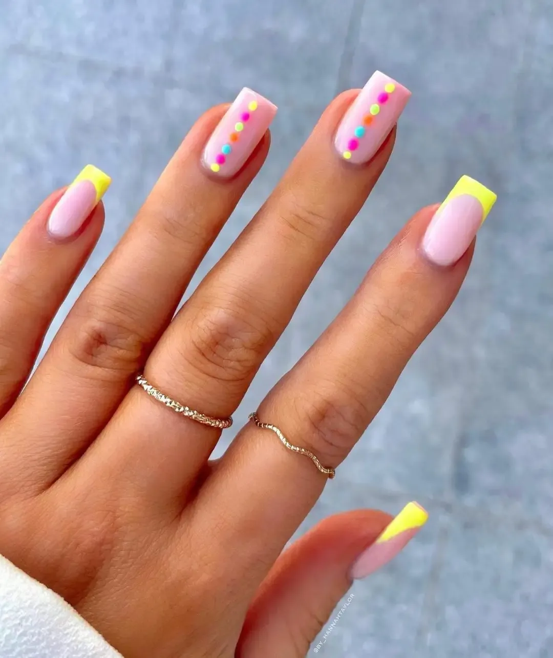 Neon yellow French tip nails with polka dots.