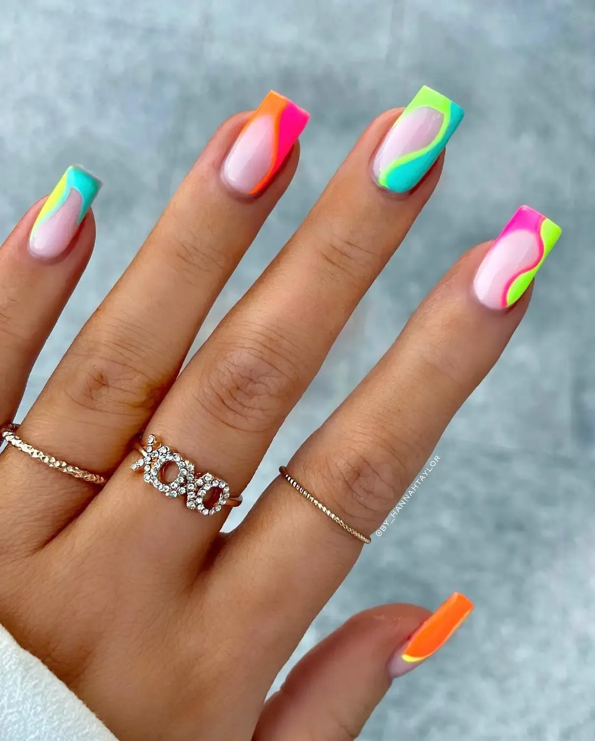 Colorful neon French tip nails with swirls.