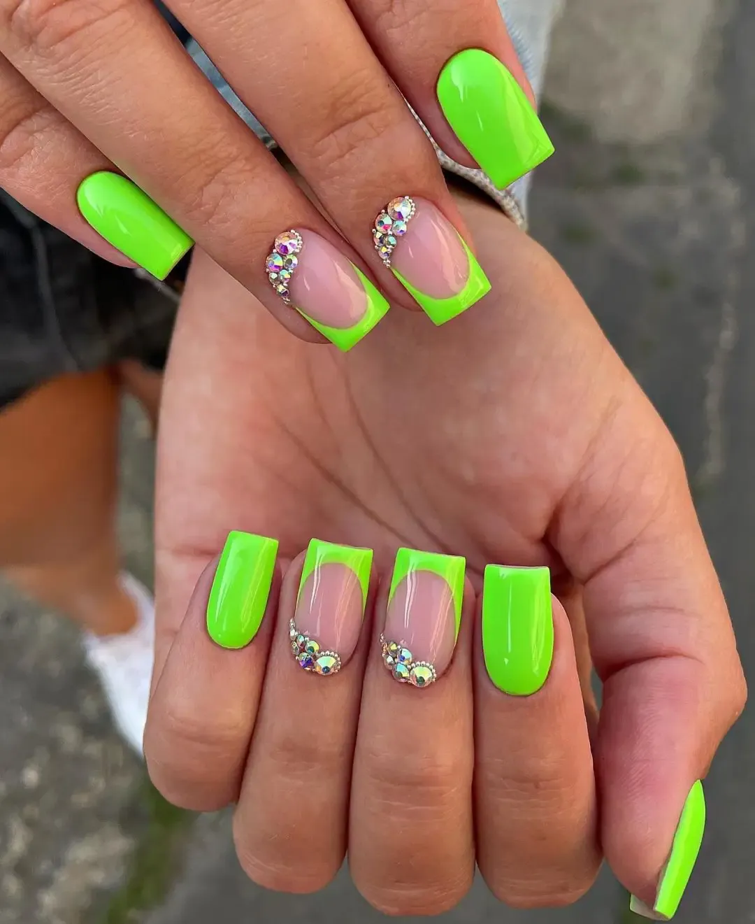 Neon green nails with French tips and crystals.