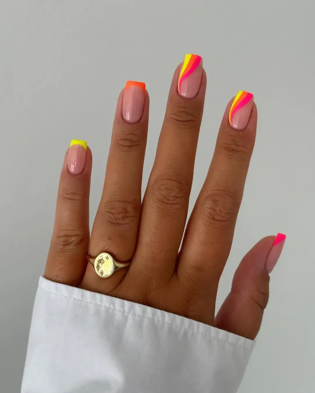 Yellow, orange and pink neon swirl nails.