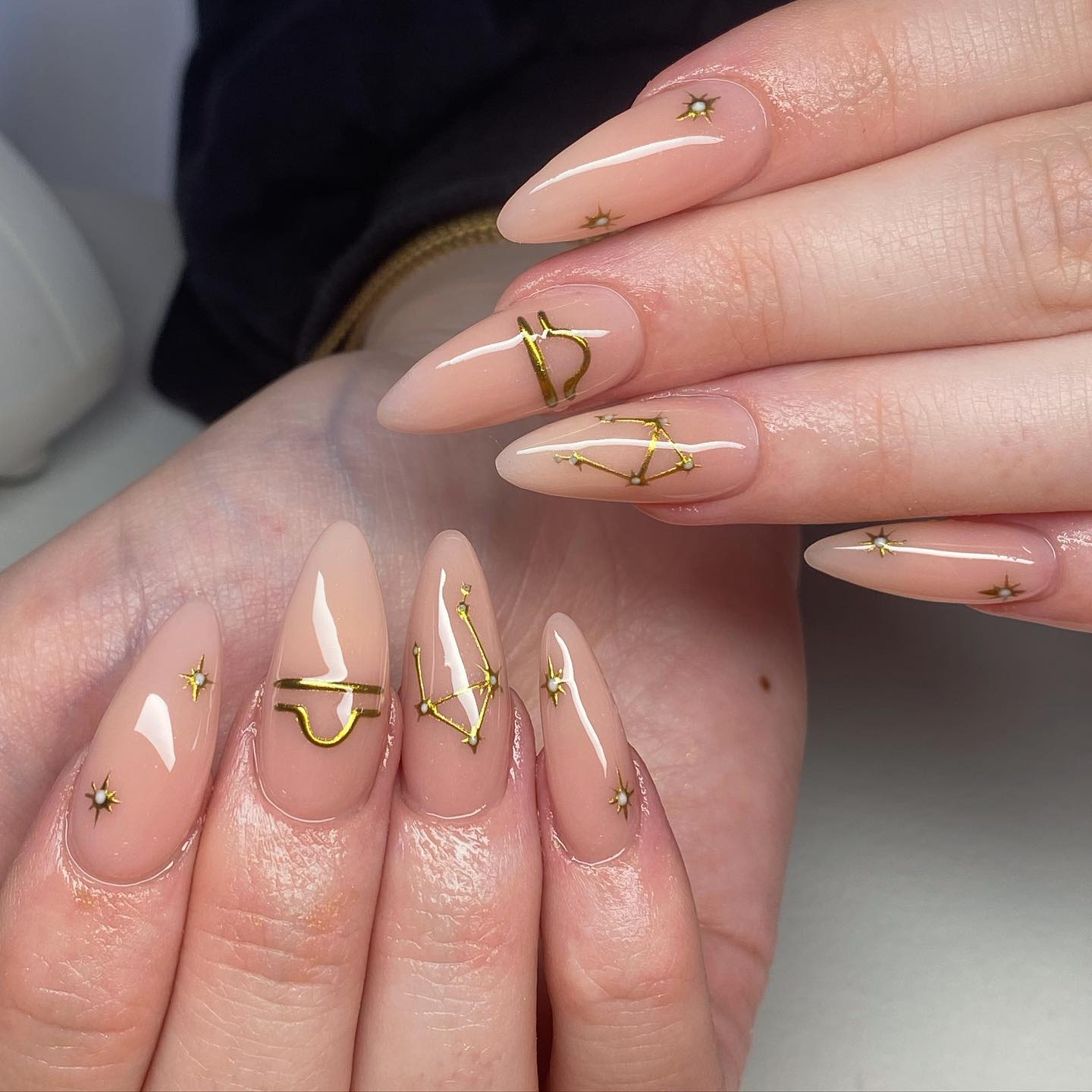 Glossy finish nude nail color with gold Libra sign and constellation nail arts on long almond nails