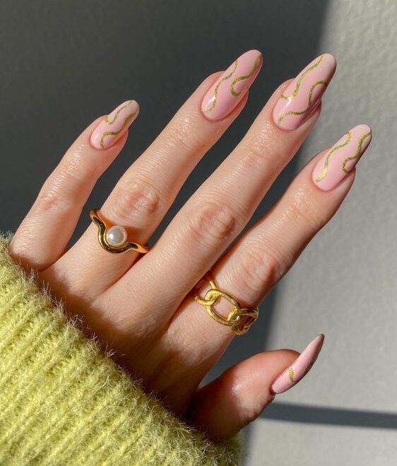 Nude pink nail color with gold swirls on long round nails