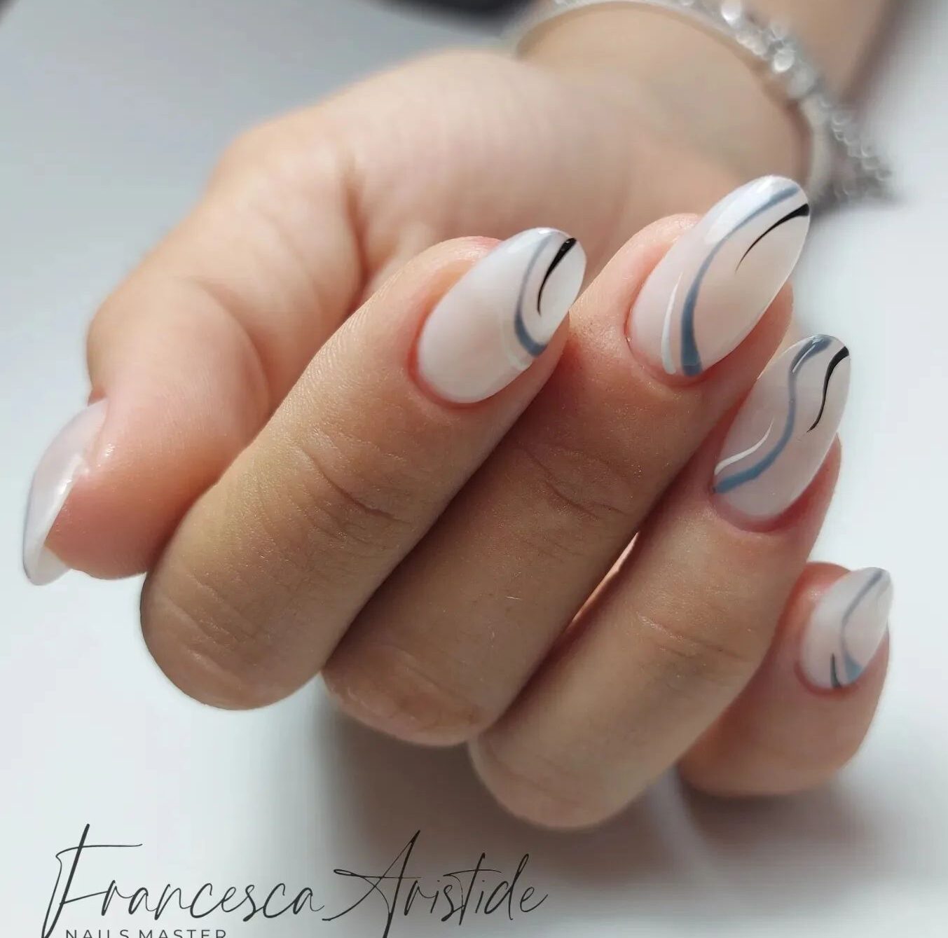 Pale white long round shaped acrylic nails with blue swirling patterns