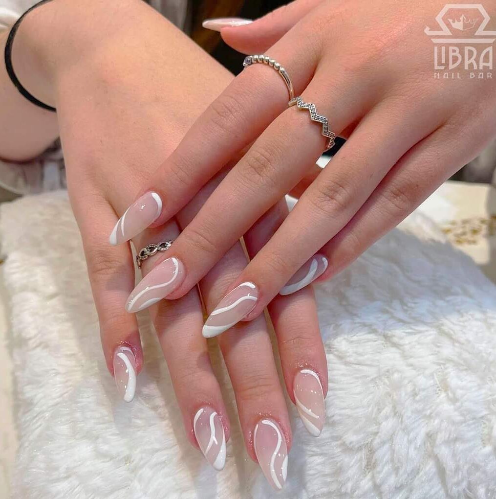 White swirls on long almond shaped acrylic nails