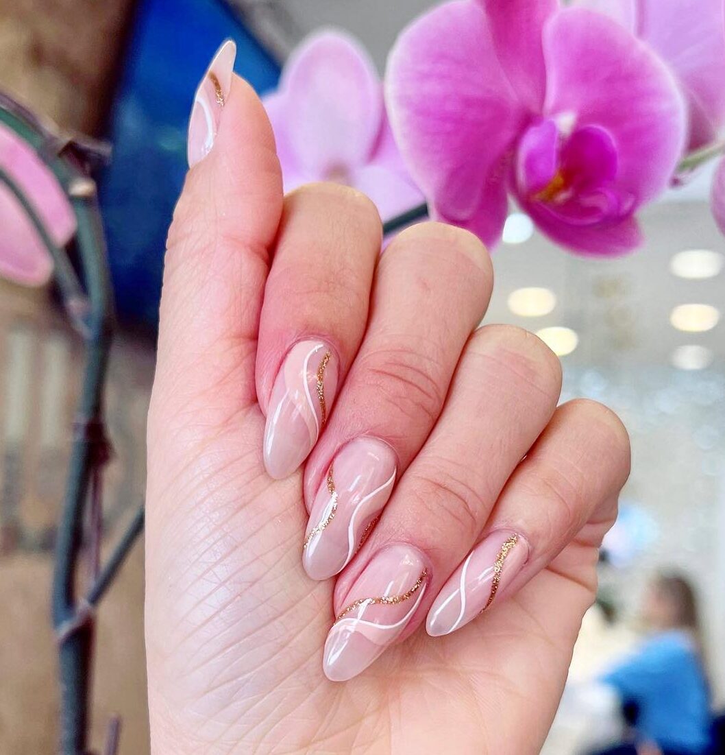 White and gold swirls on long almond shaped acrylic nails