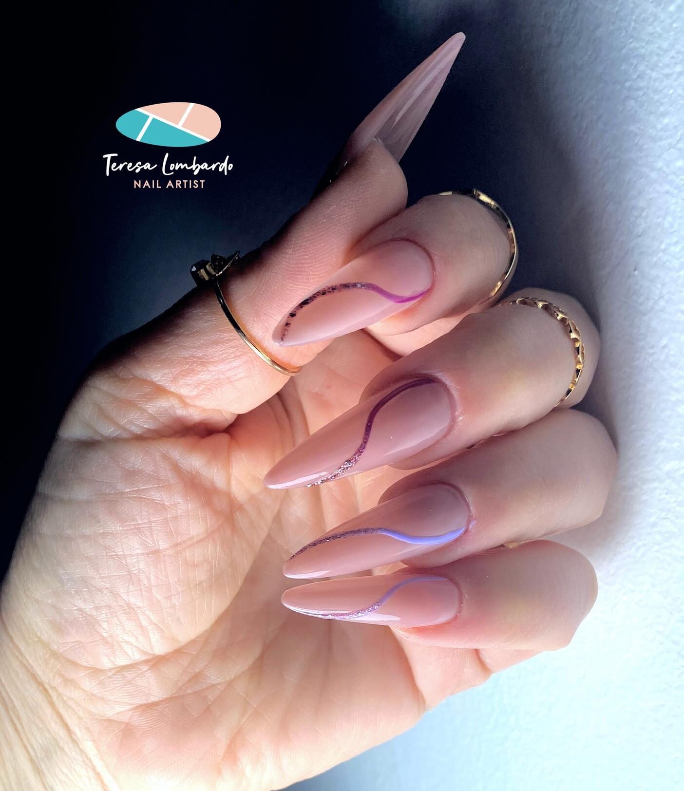 Nude nail color with swirling patterns on long stiletto shaped acrylic nails