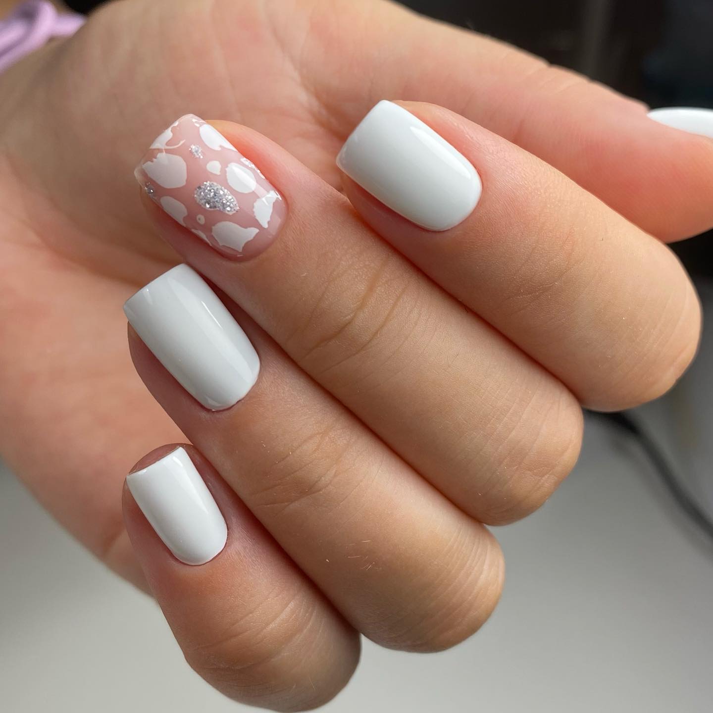 Polished white nail color with abstract nail art on short square nails